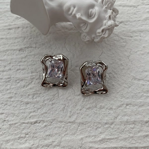Macro detail of vintage zircon stud earring featuring irregular wavy silver frame