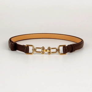 Detail view of a brown leather narrow belt featuring a gold horsebit buckle on white background
