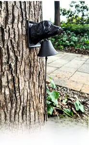 Detail showing rustic cast iron dog head doorbell with vintage texture mounted on a tree