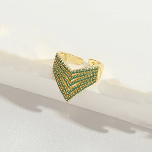 Detail of gold V-shaped adjustable ring paved with green cubic zirconia on marble