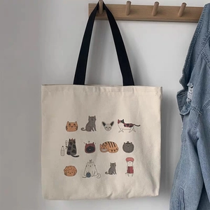 Detail of artistic canvas tote bag with 12 cute cat illustrations hanging on a wooden hook