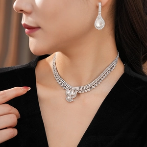Close-up of elegant silver water drop necklace and earring set with crystals on model