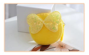 Detail view of yellow plush round coin purse featuring a shiny sequin bow and zipper