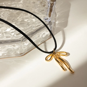 Detail view of 18k gold plated abstract bow pendant on a black cord necklace