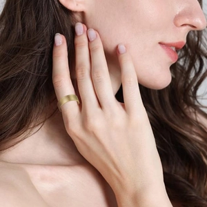 Detail of 8mm golden titanium steel ring with brushed texture worn on a finger