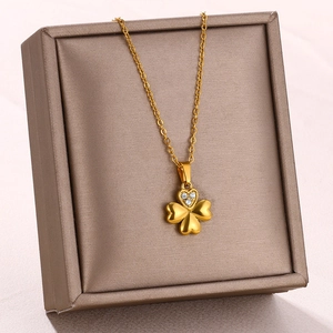 Macro detail of gold-plated clover pendant with heart leaves and zircon on a jewelry box