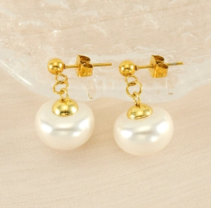 Detailed view of elegant pearl drop earrings with gold finish on textured beige fabric