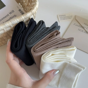 Detailed knit texture of four mid-calf socks in black, grey, mocha, and cream white