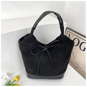 Detail of black suede tote bag featuring a leather bow knot and premium mixed textures