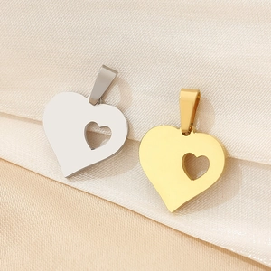 Detailed close-up of 18K gold and silver heart pendants on elegant silk fabric