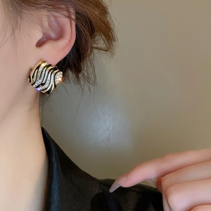 Detailed close-up of vintage gold and black striped earrings with cubic zirconia on a model