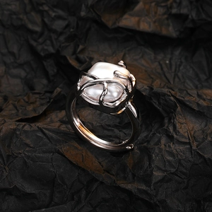 Anello con perla quadrata barocca e montatura in argento su sfondo nero rugoso