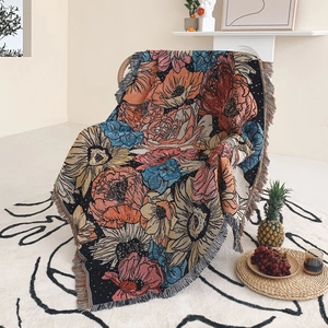 Bohemian floral woven picnic blanket with colorful tassels draped on an indoor chair