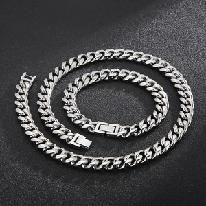 Detailed macro view of silver Cuban link chain necklace and bracelet set on black background