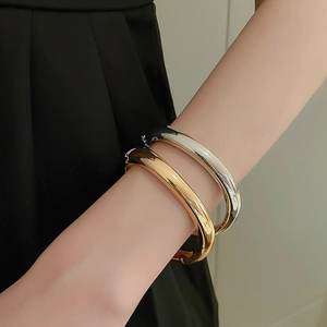 Minimalist teardrop open bangles in gold and silver set on a model's wrist