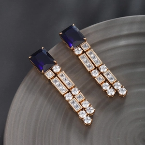 Detailed macro view of long drop earrings with blue square stones and white zircons