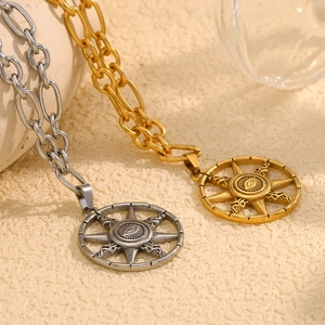 Close-up of gold and silver sunburst pendants with evil eye motif on beige fabric