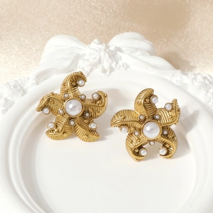 Golden starfish stud earrings with white pearls on a vintage white decorative tray