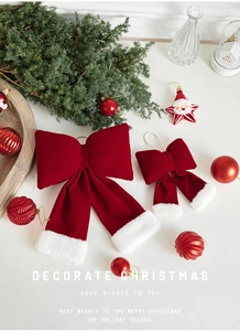 Close-up of red velvet Christmas bows with white fur trim on a festive holiday backdrop