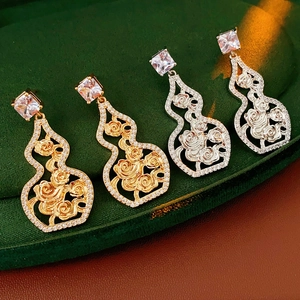 Detailed view of gourd-shaped hollow rose earrings in gold and silver with cubic zirconia