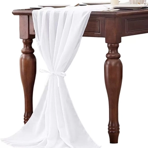 Elegant white chiffon table runner with delicate bow ties on a dark wooden dining table
