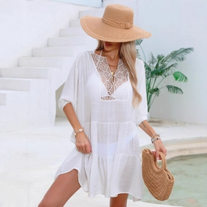 Detail of white bohemian beach cover-up featuring intricate lace crochet and tiered skirt