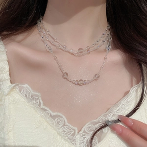 Close-up of triple-layered glass bead necklace on model with elegant lace clothing