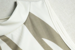 Detailed macro shot of ribbed knit fabric texture on a cream sleeveless dress