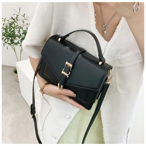 Detail shot of black structured leather crossbody bag with elegant light gold metal buckle
