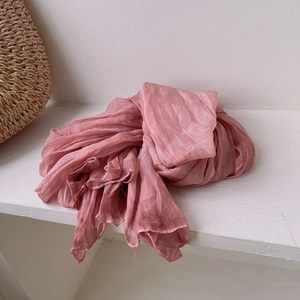Detailed texture of pink pleated scarf with retro artistic style on wooden shelf