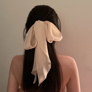 Close-up of a large soft beige silk hair ribbon bow tied on long hair from the back