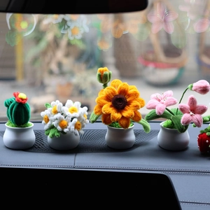 Miniature handmade pipe cleaner flower pots featuring sunflower and daisy on car dashboard