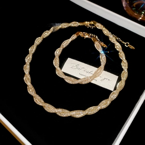 Detailed macro view of gold braided mesh twist chain necklace and bracelet jewelry set