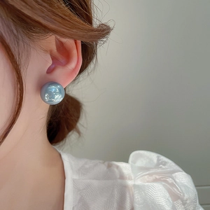 Close-up of a model wearing the light blue spherical stud earring with a glossy finish