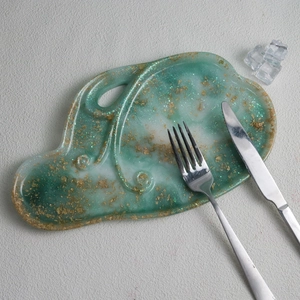 Macro shot of irregular green and white resin tray with gold foil flakes and metallic cutlery