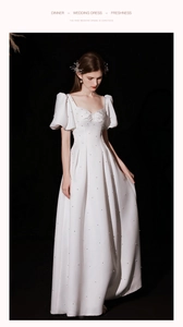Detail of white satin wedding dress featuring elegant pearl embellishments and puff sleeves