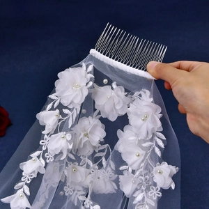 Detail of bridal veil with 3D floral lace embroidery and silver metal hair comb