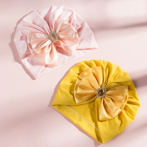 Detail of baby turban hats in pink and yellow with large rhinestone bow decoration