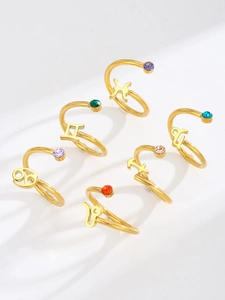 Macro detail of 18K gold plated zodiac rings with colorful zircon and engraved symbols
