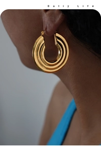 Detailed close-up of triple-layered gold hoop earrings with polished texture
