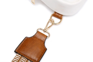 Detail of the woven shoulder strap with gold-tone hardware and brown faux leather tabs