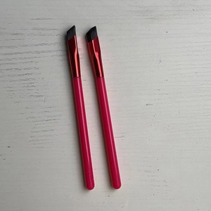 Detail of professional angled brow brushes with pink handles and red metal ferrule