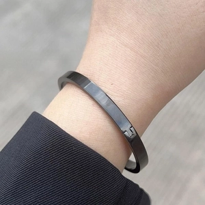 Close-up of a minimalist black stainless steel T-shape cuff bracelet on a person's wrist