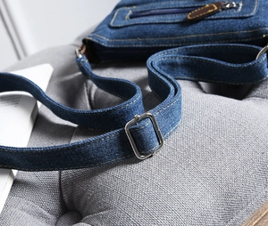Detailed macro view of denim crossbody bag with adjustable silver buckle and blue strap