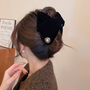 Détail d'un grand nœud en velours noir avec fleur de perle sur les cheveux d'un modèle