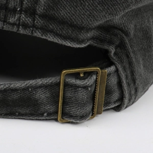 Detailed close-up of an adjustable bronze metal buckle on a washed cotton baseball cap