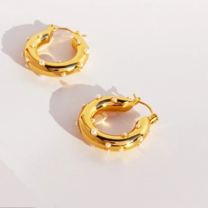Elegant gold chunky hoop earrings featuring inlaid white pearls for a modern luxury look
