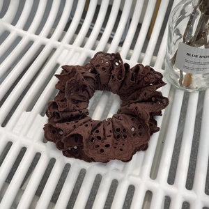 Elegant dark brown lace scrunchie with intricate embroidery on white striped background