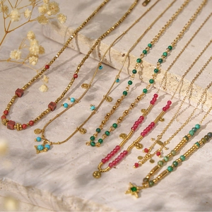 Detailed close-up of gold stainless steel beaded necklaces on a natural stone surface