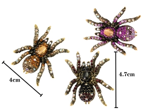 Detailed size view of spider brooches in purple and orange with rhinestone inlay